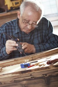 Senior carpenter carving wood with engraver tool. Restoring the old furniture.